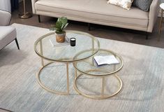 two glass tables sitting on top of a rug in front of a couch and coffee table