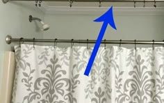 a blue arrow pointing to the left in front of a white curtain with grey damask