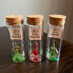 three glass jars filled with tiny beads and corks on top of a wooden table