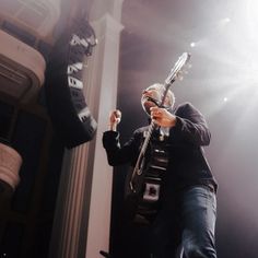 a man holding a guitar while standing in front of a building