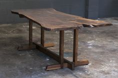 a wooden table sitting on top of a cement floor next to a brick wall in an empty room