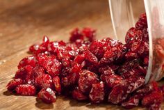 a plastic container filled with cranberries sitting on top of a wooden table next to a knife