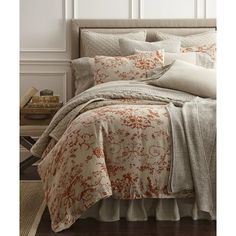 a bed with an orange and white flowered comforter on it's side