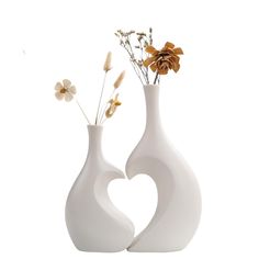 two white vases with flowers in them on a white background, one is shaped like a heart