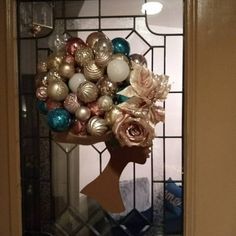 a wreath made out of ornaments in front of a door with a person's head on it