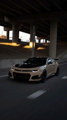 a white sports car driving down the road at night in front of an overpass