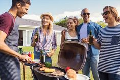 a group of people standing around a bbq grill with drinks and food on it