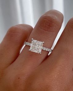 a woman's hand with a diamond ring on top of her finger and an engagement band