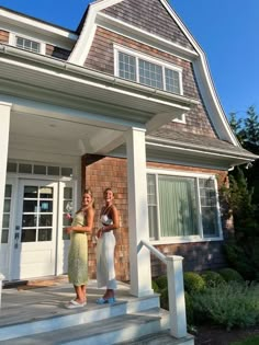 two women standing on the front steps of a house