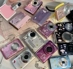 many different types of cameras sitting on top of a table next to each other with hello kitty stickers all over them