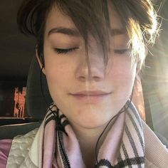 a woman with her eyes closed in the back seat of a car while wearing a scarf