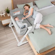 a woman laying on top of a bed next to a baby