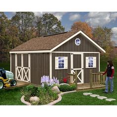 a woman standing in front of a shed with a lawn mower next to it