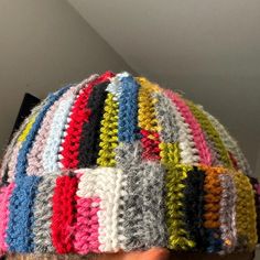 a close up of a person wearing a knitted hat with multicolored stripes