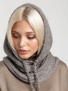 a woman with blonde hair wearing a gray knitted scarf and cowl neck sweater