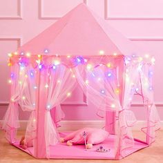 a pink play tent with fairy lights on it