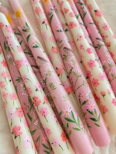 six pink and white candles with flowers painted on them