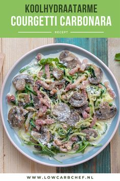 a white plate topped with pasta covered in mushrooms and spinach on top of a wooden table