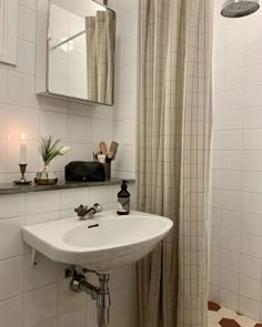 a white sink sitting under a bathroom mirror next to a bathtub with a shower curtain