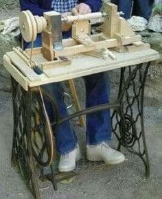 a man sitting at a table working on an old fashioned sewing machine