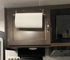 a kitchen area with microwave, stove and towel dispenser on the wall