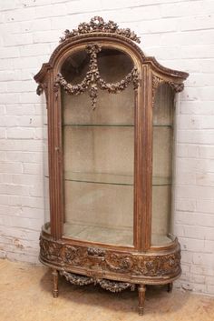 an old wooden china cabinet sitting against a white brick wall