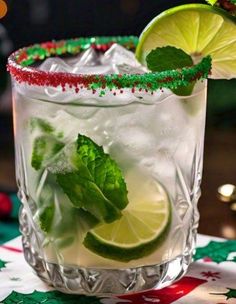 a close up of a drink in a glass with limes and peppermint garnish