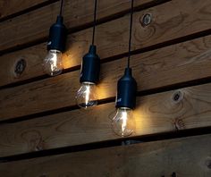 three light bulbs hanging from a wooden wall