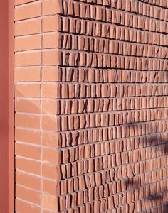 a red brick wall with the shadow of a person standing on it's side