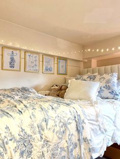 a bed with blue and white comforter in a bedroom next to pictures on the wall