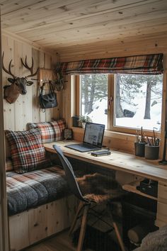 a laptop computer sitting on top of a wooden desk next to a window filled with deer heads