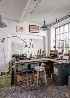 an old fashioned workbench with lots of tools on the table and two stools in front of it