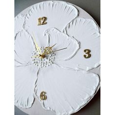 a white flower clock with gold numbers on it