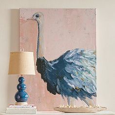 a painting of an ostrich on a wall next to a table with a lamp