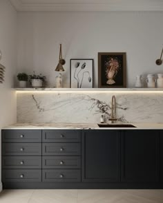 an elegant kitchen with marble counter tops and black cabinetry, along with gold pulls