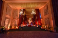 an indoor wedding venue with chandeliers and red drapes