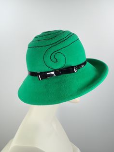 This pretty Kelly green medium brim hat is hand blocked over a vintage hat block and hand sewn. The asymmetrical brim rolls upward in the front and on the left side. Millinery wire is sewed inside of the brim edge to help the hat keep it's shape. The band is a gorgeous vintage patent leather with a matching bow. The top of the hat is hand embroidered in a swirl pattern in black cotton floss. An inner grosgrain headband helps avoid damage from makeup. Gorgeous in every way!+++++++++++++++++++++++ Adjustable Green Fedora Felt Hat, Adjustable Wide Brim Green Felt Hat, Green Hat Bands For Kentucky Derby, Green Adjustable Felt Hat For Kentucky Derby, Green Fedora For Kentucky Derby, Green Adjustable Short Brim Hat, Fitted Green Brimmed Fedora, Green Tailored Brimmed Fedora, Vintage Green Fedora With Curved Brim