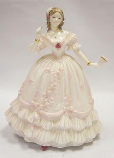 a porcelain figurine of a woman wearing a dress and holding a flower in her hand