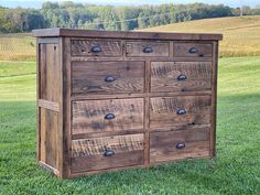 a wooden dresser sitting on top of a lush green field