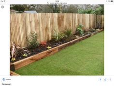 a wooden fence is next to a grassy area with flowers and plants in the middle