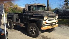 an old black truck is parked on the street