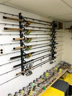 there are many fishing rods hanging on the wall in this room with yellow bins