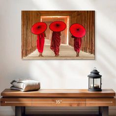 two monks with red umbrellas walking down a hallway