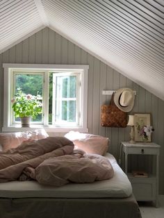 an unmade bed in a room with two windows and pillows on top of it