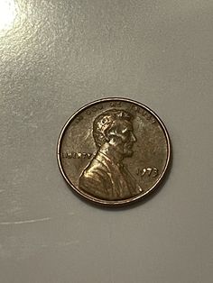 a penny is sitting on top of a white countertop with the image of a man's head