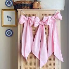 two pink bows are hanging on the side of a cabinet