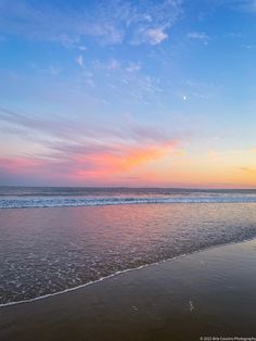 the sun is setting at the beach with waves coming in