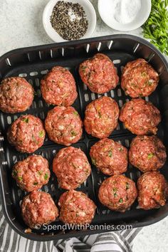 meatballs are being cooked in an air fryer with spices and seasonings on the side