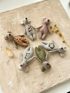 five stuffed animals are arranged on a table top with beads and flowers in the background