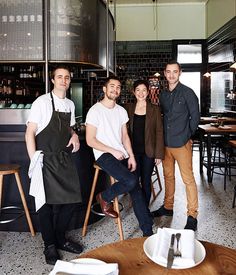 three men and two women standing in a restaurant